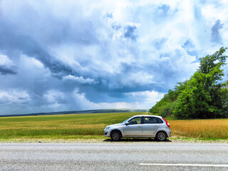Empty country road stretching into distance under cloudy sky, rural landscape and fields, calm travel mood, journey and movement concept in overcast weather