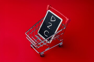 Mini shopping cart holding a chalkboard with D2C text. Direct to consumer business model, ecommerce concept.