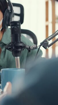Vertical Screen : Asia girl radio host record podcast use microphone wear headphone interview guest content wear mask protect virus conversation talk and listen in room. Podcast from home, quarantine.