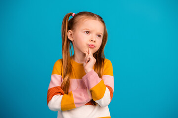 Young girl with colorful sweater poses thoughtfully against blue background