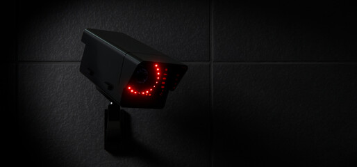 Black CCTV Security Camera with Red LED Lights on Dark Wall