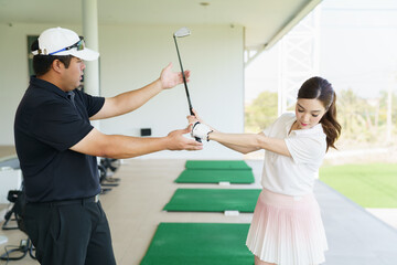 Golf instructor giving personal lesson to woman at driving range.