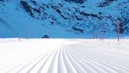Groomed ski slope with corduroy snow texture, featuring bright pink markers, showcasing pristine winter landscape and inviting conditions for skiing and snowboarding enthusiasts