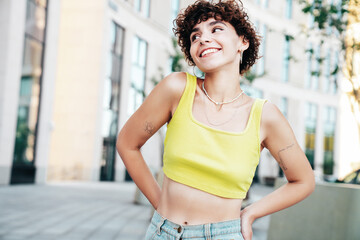 Young beautiful smiling hipster woman in trendy summer clothes. Carefree woman with curls...