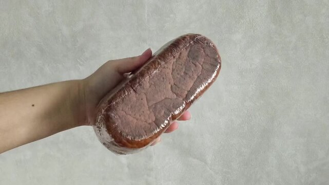 Rye loaf of bread in transparent packaging in a woman's hand. Bread products made from dark flours. Cereals