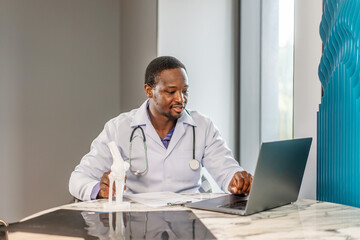 Male doctor is explaining something using an anatomical model bone while having online consultation with a patient, talking scoliosis, herniated discs, osteoporosis, diagnosing bone density issues