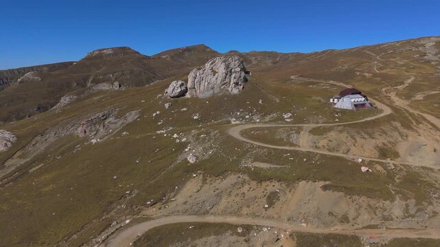 Aerial Orbit Panorama of Salvamont Busteni Cabin and Baba Mare Peak with Ialomita Valley Erosion Background 4K