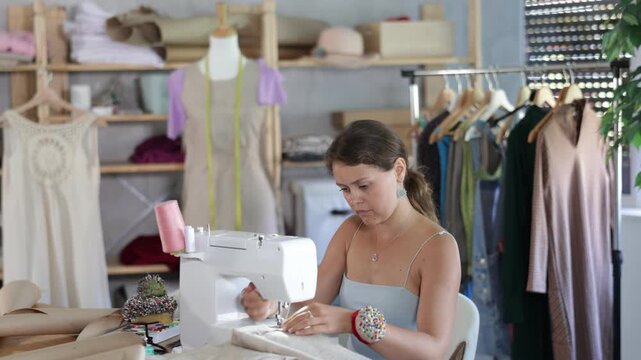 Female clothing designer stitching fabric on sewing machine in studio 