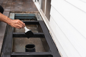 A professional painter is applying anti rust paint to a steel balcony outside a house.