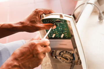 Close up of man repairing motherboard with screwdriver.