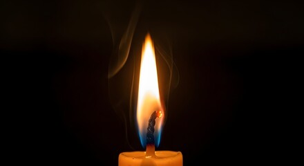 Close up of a single burning candle flame with wisps of smoke gently rising against a deep black background in the darkness