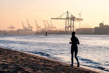 A jogger at the beach at the Elbe River in Hamburg at sunrise