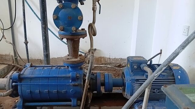 Old multi-stage centrifugal water pump operating, vintage industrial machinery in a water plant.