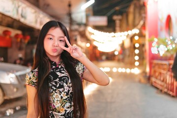 Young Girl Celebrating New Year with Peace Sign in Festive Alley