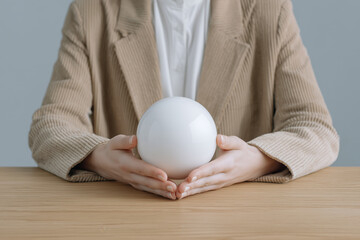 Businesswoman holding white sphere on wooden desk in modern office