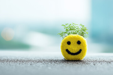 Smiling yellow plant symbol on textured surface with blurred background