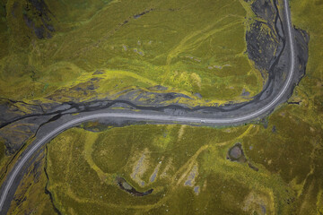 curvy road cutting through moss-covered lava fields near Solheimsjokull Glacier in southern Iceland
