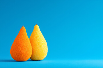 Vibrant orange and yellow pears on bright blue background