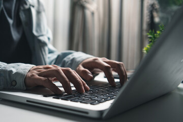 Hand typing on laptop keyboard at home office workspace. Freelancer working online, using computer for business, education, coding, and digital marketing concept. Representing work productivity, 