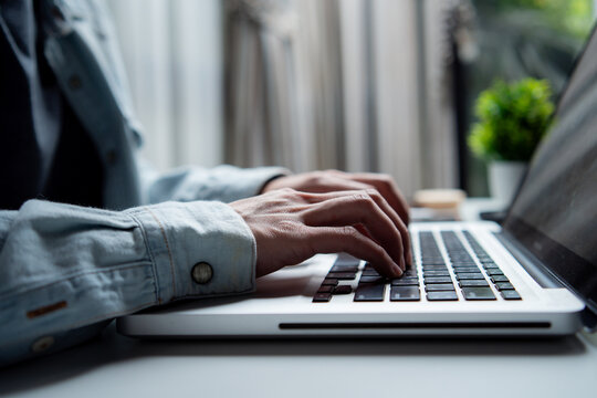 Hands typing on laptop keyboard. Professional man working on computer at desk. Freelance, remote work, program coding, research marketing, search data and digital nomad concept - Powered by Adobe