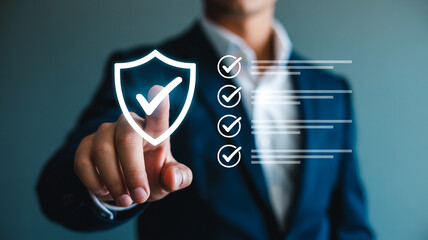 Businessman in blue suit jacket interacting with digital shield and checklist icons for security and protection with cybersecurity