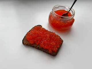 Red caviar. A spoon in a jar of caviar.