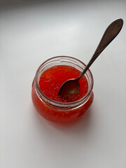 Red caviar. A spoon in a jar of caviar.
