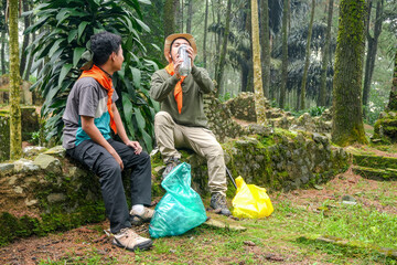 Two Hikers Taking Break Amidst Ancient Mossy Ruins in Lush Forest