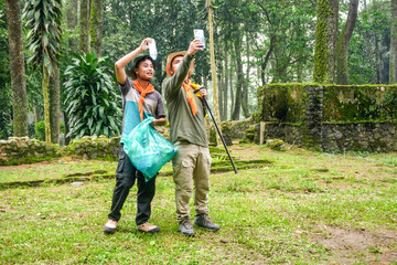Two Young Men Happily Collecting Trash in Lush Green Forest