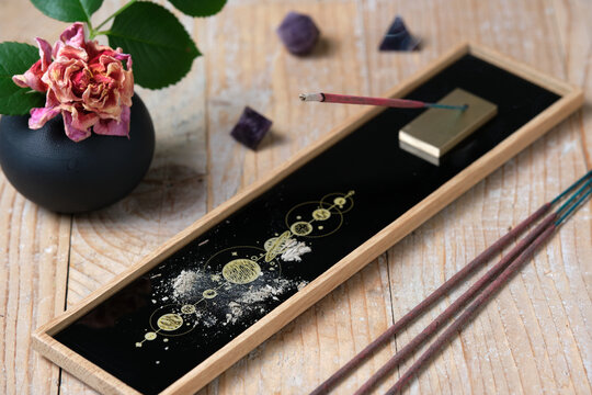 Burning incense stick with smoke on decorative holder with cosmic pattern