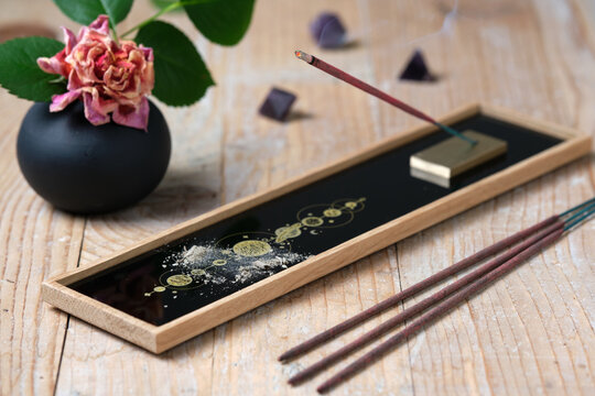 Burning incense stick with smoke on decorative holder with cosmic pattern
