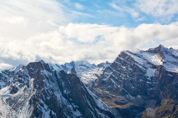 Snow-covered mountains stand as majestic white giants against sky, embodying winter's powerful alpine beauty.