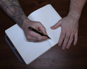 Male hands with open notebook and pen on wooden table