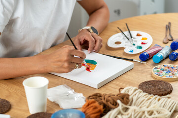 Woman engaged in home painting activity with organized craft setup. Emphasizes creativity, fine motor control, and enjoyable artistic learning.