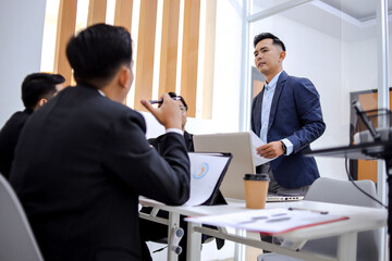 Confident Businessman Presenting To Engaged Colleagues In Bright Modern Office