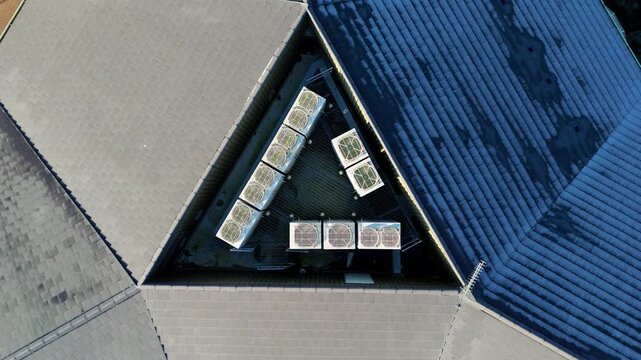 Top down aerial drone view of HVAC air conditioning units and cooling fans in triangle symmetrical formation data centre, quantum cloud storage and IT information in Technology park, UK