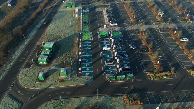 Top down aerial view of EV electrical vehicle charging hubs, modern car technology, no fossil fuels at a service station in the United Kingdom.