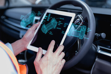 Technician using tablet to analyze electric vehicle system with virtual interface, inspecting battery and engine diagnostics inside car. Concept of EV maintenance and smart technology.