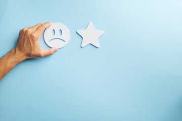 Bad customer feedback shown by hand placing sad face emoji icon, indicating poor service review, unhappy experience, business satisfaction survey response for consumer complaint