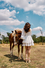 Woman standing with horse outdoors under blue sky in peaceful rural setting