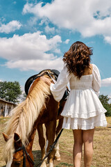 Woman standing with horse outdoors under blue sky in peaceful rural setting