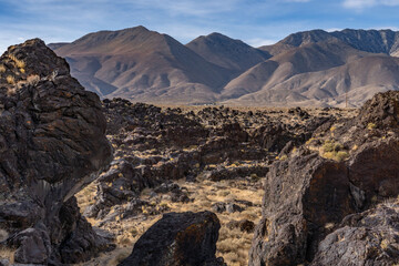 Fototapeta premium Volcanic rock, Basalt flows. Fossil Falls Trail, Coso Volcanic Field, Inyo County, California. Coso Range, Basin and Range Province. In the distance is Sierra Nevada ( mountain range )