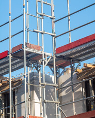 Construction scaffolding supports building work on a sunny day at a construction site in progress near the city center