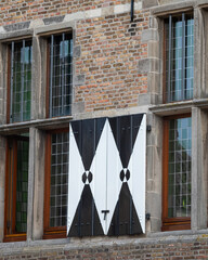 Unique window shutters adorned with geometric designs on a historic building in a European city