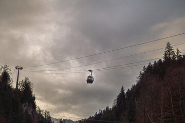 Cable car crossing a mountain valley under cloudy sky
