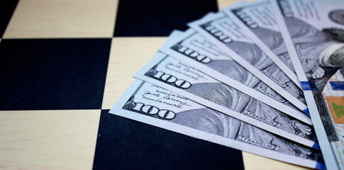 One hundred American dollars close-up on a chessboard background. National currency of the United States of America