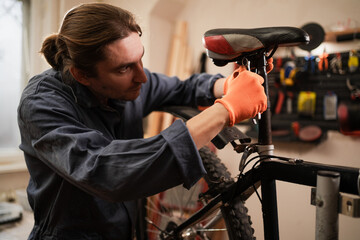 Bike service, repair and upgrade concept. Male Cycling mechanic fixing bicycle seat in garage. repairman in workshop.