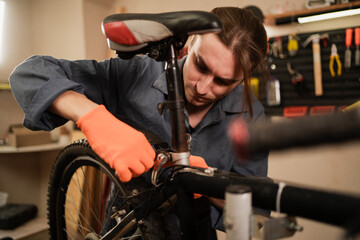 Bike service, repair and upgrade concept. Male Cycling mechanic fixing bicycle seat working in garage. cycle repairman in workshop.