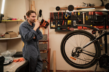 Bike service, repair and upgrade concept. Male Cycling mechanic drinking coffee resting after...