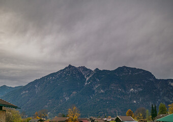 Mountain massif rising above a village under cloudy sky